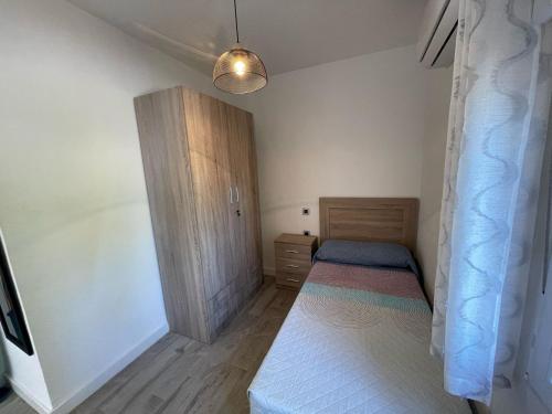 um quarto com uma cama e um armário de madeira em Doamvid Universidad em Ciudad Real