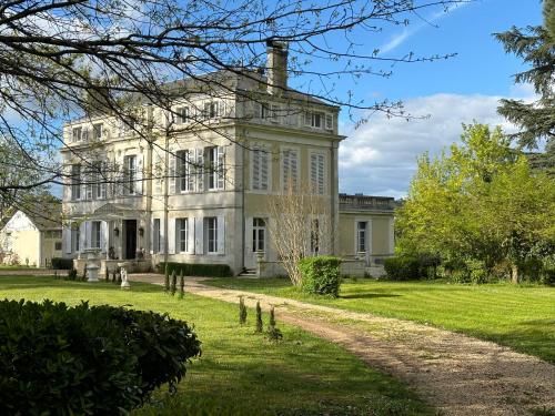 La maison au cèdre في Marsac-sur-lʼIsle: منزل أبيض كبير مع ساحة عشبية