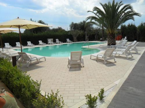 einen Pool mit Stühlen und einem Sonnenschirm in der Unterkunft Hermes Hotel in Policoro