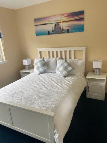 ein Schlafzimmer mit einem weißen Bett und zwei Nachttischen in der Unterkunft Gateway to the Loch in Balloch