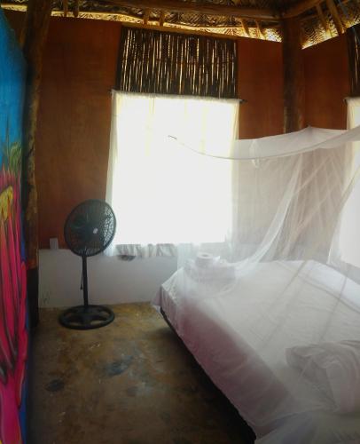 a bedroom with a bed and a window with a fan at Zirumake Hostel Dentro del Parque Tayrona in El Zaino
