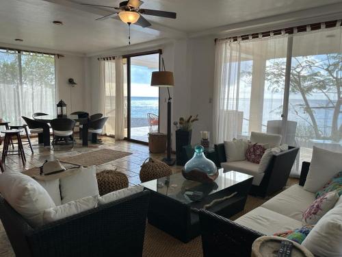 a living room with couches and a dining room with the ocean at VILLA FLOREANA in Puerto Velasco Ibarra
