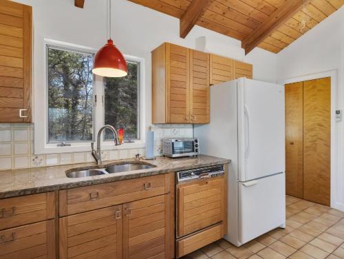 a kitchen with wooden cabinets and a white refrigerator at Stylistic Home and Easy Walk to the Beach in Truro