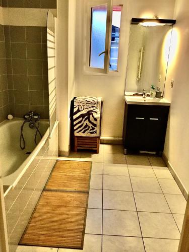 une salle de bain avec une baignoire, un lavabo et un miroir dans l'établissement APPARTEMENT T2 VELODROME PRADO, à Marseille