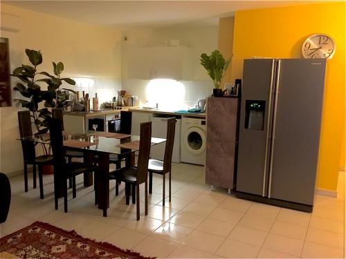 une cuisine avec une table et un réfrigérateur en acier inoxydable dans l'établissement APPARTEMENT T2 VELODROME PRADO, à Marseille