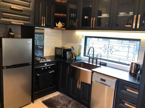 a kitchen with black cabinets and a stainless steel refrigerator at Tiny Home Luxury Farm Escape in Egmont Village