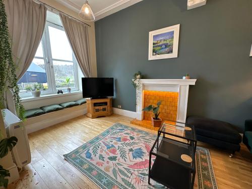 1 The Cairn Kilmartin - Beautiful Victorian Flat, Pet Friendly في Kilmartin: غرفة معيشة مع موقد وتلفزيون