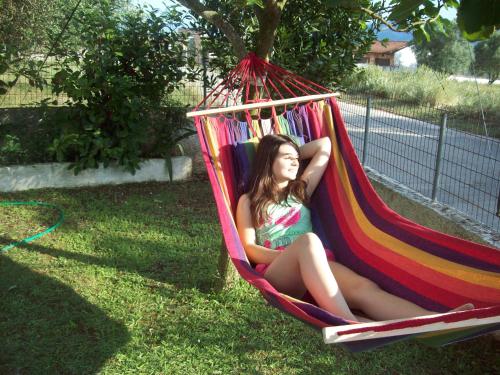 a girl sitting in a hammock in a yard at Mιχαλης Apartments in Paramythia