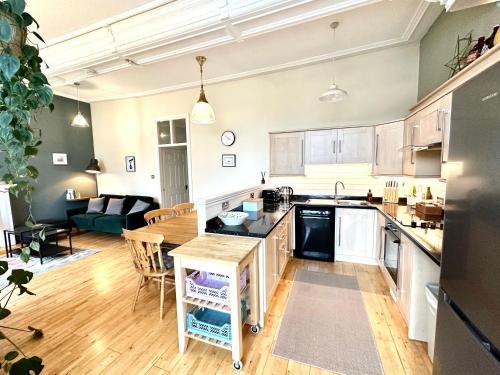 1 The Cairn Kilmartin - Beautiful Victorian Flat, Pet Friendly في Kilmartin: مطبخ مفتوح وغرفة معيشة مع أريكة