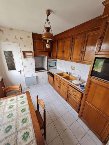 a kitchen with wooden cabinets and a table and a sink at Le clos tranquille in Blois