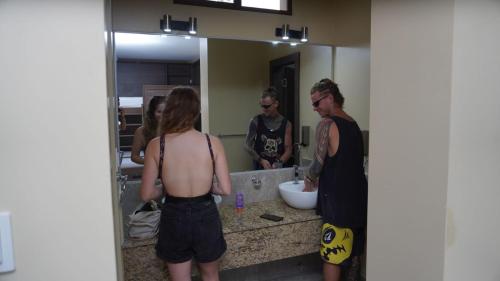 a group of people standing in front of a bathroom mirror at Paradise Project Hostal in Montañita