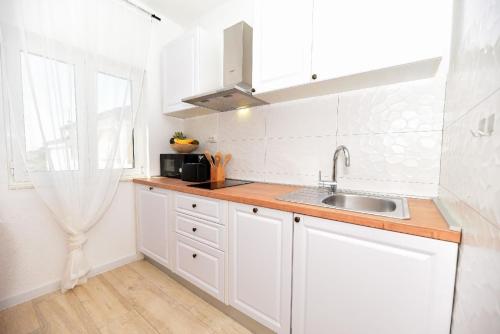 a kitchen with white cabinets and a sink at Ferienwohnung für 2 Personen 1 Kind ca 40 qm in Ljubač bei Zadar, Dalmatien Norddalmatien in Ljubač
