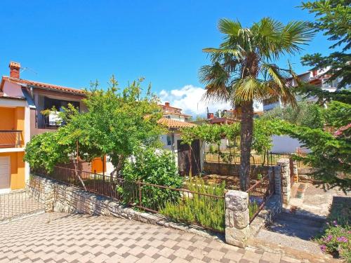a house with a fence and a palm tree at Ferienwohnung für 5 Personen ca 70 qm in Stinjan, Istrien Istrische Riviera in Štinjan