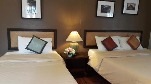 a hotel room with two beds and a table with a lamp at Baan Warabordee in Chiang Rai