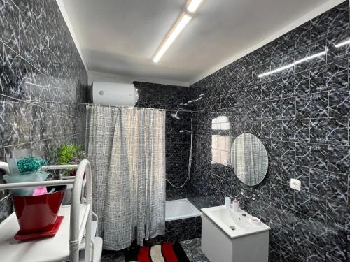 a black tiled bathroom with a toilet and a sink at Villa Oni in Tirana