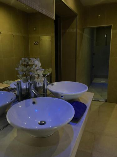 łazienka z 2 umywalkami i kwiatami na ladzie w obiekcie Grove House Rooms w Cork