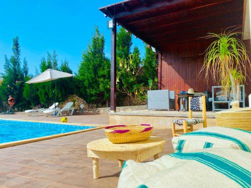 a pool with two beds and a table next to a pool at Villa Sunset Moulay Bouzerktoun in Essaouira