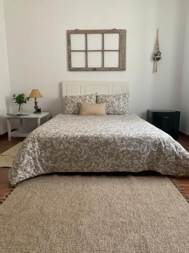 um quarto com uma cama com um cobertor e uma janela em Monte Sul da Pintada em Montemor-o-Novo