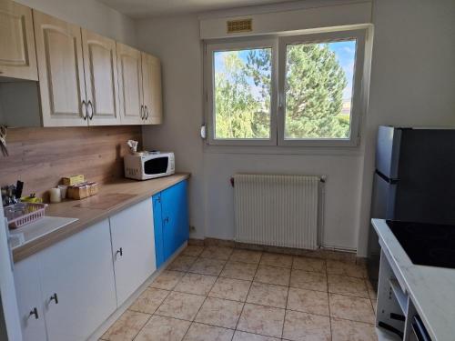eine Küche mit weißen Schränken und einem Fenster in der Unterkunft location appartement 80m2 à Rombas in Rombas