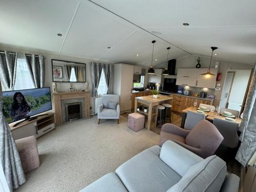 a living room with a couch and a tv at Golden Anchor - The Waverley - Coastal Caravan Breaks in Chapel Saint Leonards