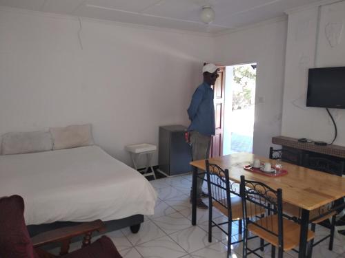 um homem de pé numa sala com uma cama e uma mesa em Brackendene Lodge em Gaborone