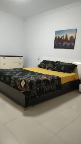 Schlafzimmer mit einem Bett mit einer schwarzen und gelben Tagesdecke in der Unterkunft Mobilart in Oran