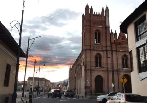 an old church with a clock tower on a city street at La Merced Plaza Hospedaje in Riobamba