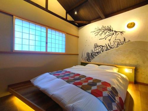a bedroom with a bed with a painting on the wall at 旅宿うさぎとかめ Guest House USAGI to KAME 近江八幡中心地 ヴォーリズ建築好きにお勧め in Hachiman