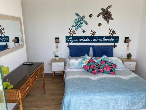 1 dormitorio con 1 cama con sábanas azules y flores en frente al mar San Bartolo en San Bartolo