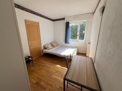 um pequeno quarto com uma cama e uma mesa em Magnifique appartement de 90m2 dans une zone pavillonnaire d'Evry em Courcouronnes