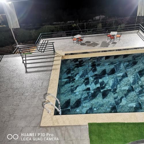 a swimming pool with two tables and two chairs at Musk of night chalet in Jerash