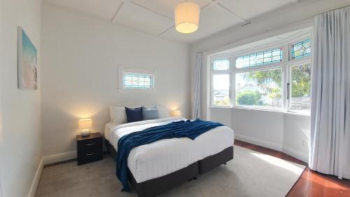 a white bedroom with a bed and a window at Kingsland Family Home in Auckland