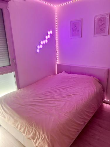 ein Schlafzimmer mit einem Bett mit violettem Licht in der Unterkunft Chambre à louer avec salle de bain privative in Carrières-sous-Poissy