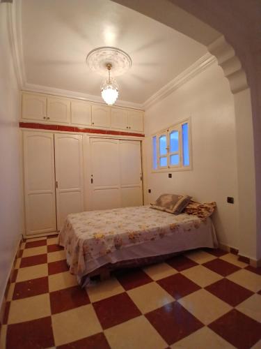 een slaapkamer met een bed en een geruite vloer bij Dar zahra in Aourir