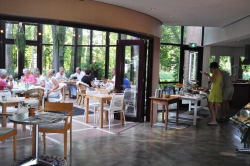 a group of people sitting at tables in a restaurant at Droste's Herberg in Tubbergen