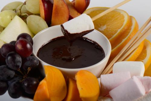 a plate of fruit and a bowl of chocolate on sticks at Cabin Resort in Moshav Ramot