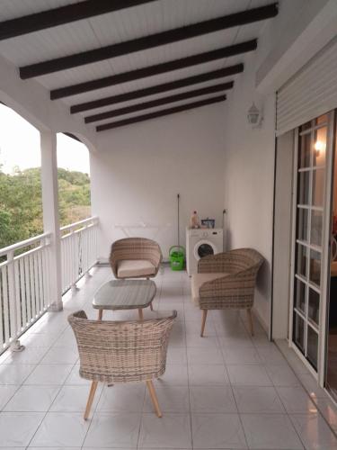 a balcony with wicker chairs and a table at LE VERDOYANT in Sainte-Anne