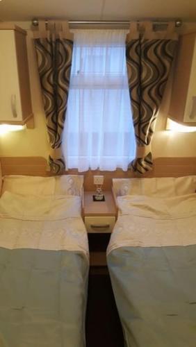 2 camas en una habitación pequeña con ventana en Cozy and relaxing with stunning sea views, en Lytchett Minster