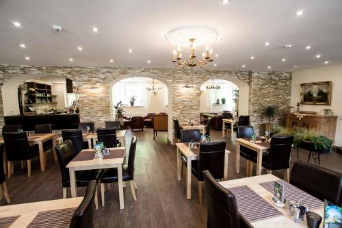 a restaurant with tables and chairs and a stone wall at Waldhotel Bad Jungbrunn in Tristach