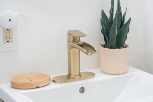 a bathroom sink with a gold faucet and a plant at Retro Retreat: 1br home w/ WFH desk, livingroom, and fire pit in Kingston