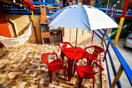 a red table and four red chairs under an umbrella at Casa do Passarinho in Campos do Jordão