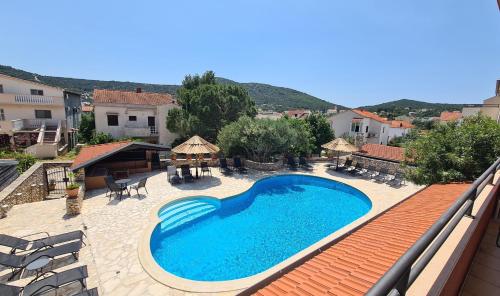 a large swimming pool on a patio with chairs and umbrellas at Red House Apartment With Swimming Pool in Vinišće