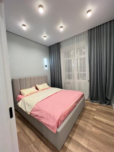 um quarto com uma cama grande e um cobertor rosa em Новая квартира возле Меги и экспо em Taldykolʼ