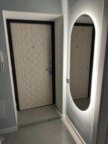 um corredor com duas portas com um espelho redondo em Новая квартира возле Меги и экспо em Taldykolʼ