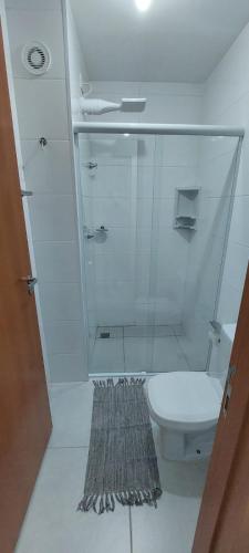 La salle de bains est pourvue de toilettes et d'une douche en verre. dans l'établissement Condomínio da Fé, pertinho da Canção Nova, Flat Nossa Senhora Do Rosário, estacionamento gratuito., à Cachoeira Paulista