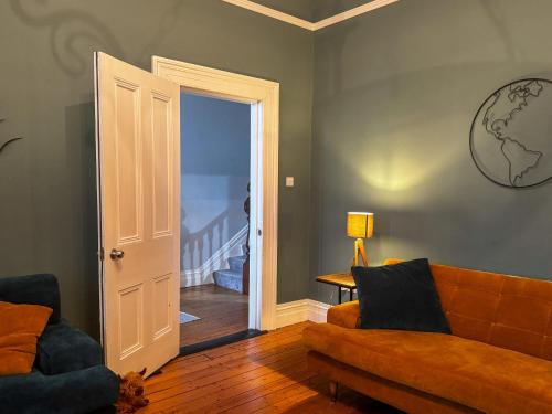 a living room with a couch and an open door at The Victorian Townhouse Portrush in Portrush