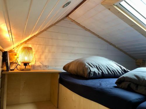 a bed in a room with a lamp on a table at Tinyhouse_Nordfriesland in Bargum