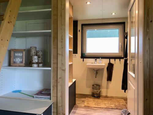 ein Bad mit einem Waschbecken und einem Fenster in der Unterkunft Tinyhouse_Nordfriesland in Bargum