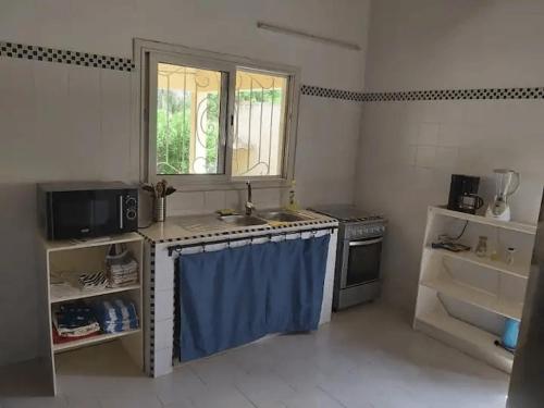 a kitchen with a sink and a stove and a window at Chez Jacques Diatta in Cap Skirring