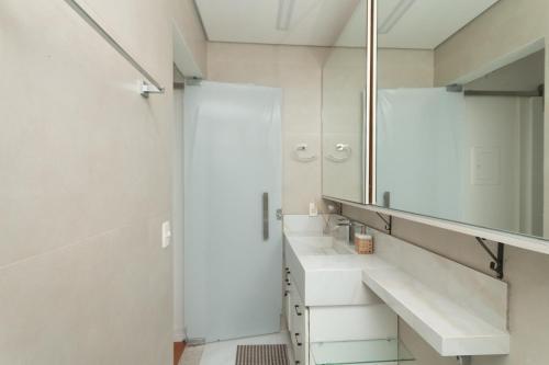 un bagno con doccia, lavandino e specchio di Volpi Residence na Savassi - charme, localização e conforto a Belo Horizonte